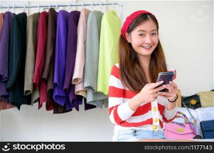 Beauty Asian Vlogger blogger selling woman clothes and bag online during using phone on social media. Woman coaching trading and review product. Business presentation. Looking at camera portrait