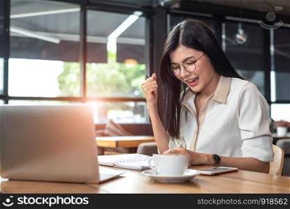 Beauty Asian woman having cheerful gesture after finishing job happily with laptop computer in cafe. People and lifestyles concept. Technology and Business working theme. Occupation and job theme.