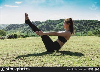 Beauty Asian woman practice yoga boat pose or Navasana pose stretching exercise muscle with yoga meditation relax and refresh health on green grass feeling happiness and comfortable,Healthcare Concept