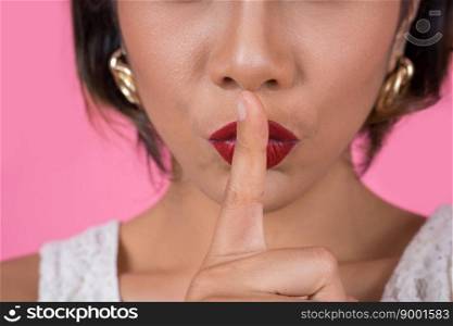 Beauty asian woman red lips and finger showing hush silence sign

