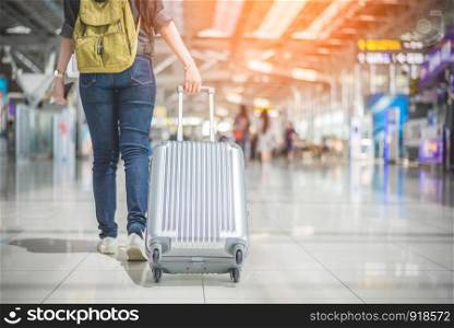 Beauty Asian woman traveling and holding suitcase in the airport. People and Lifestyles concept. Travel around the world theme. Back view and lower angle.