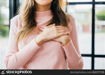 Beauty Asian young woman touching her chest for thanking at home, happy charming female smiling hold hands chest near heart honest with grateful gesture