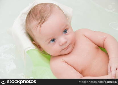 Beauty baby boy having bath at bathing stand