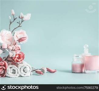 Beauty background with pastel pink flowers and cosmetic at pastel blue background
