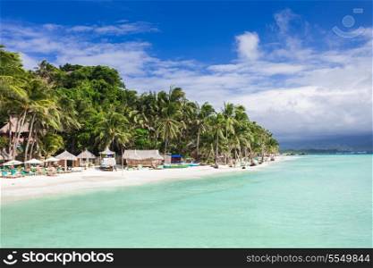Beauty beach with coconut palms on the blue sky background