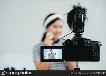 Beauty blogger present beauty cosmetics while sitting in front c. Beauty blogger present beauty cosmetics while sitting in front camera for recording video. Beautiful woman use powder while review make up tutorial broadcast live video to social network by internet.