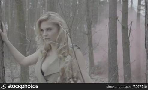 beauty blonde woman in the forest with the smoke behind