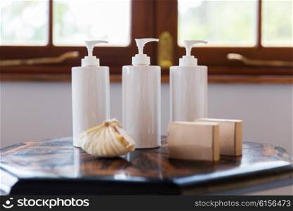 beauty, body care, luxury, natural cosmetics and hygiene concept - close up of liquid soap or body lotion set at hotel bathroom