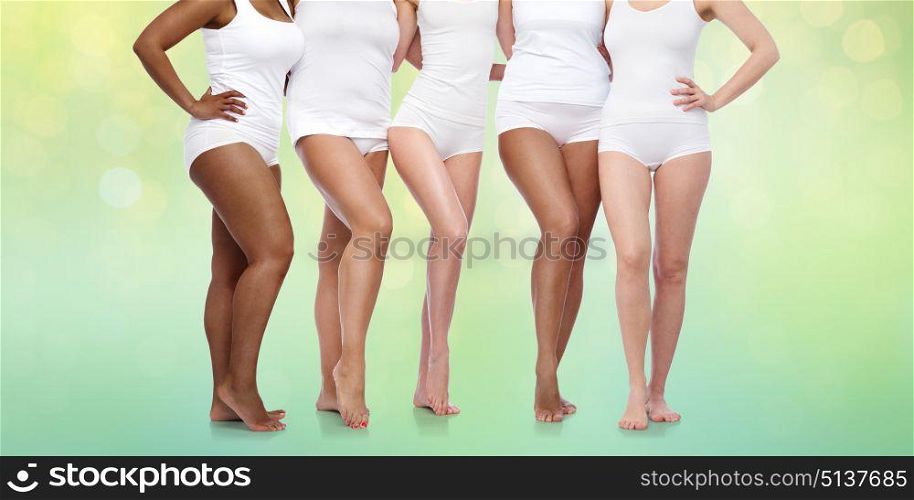 beauty, body positive and people concept - group of diverse women in white underwear over summer green lights background. group of happy diverse women in white underwear. group of happy diverse women in white underwear