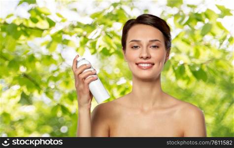 beauty, bodycare and natural cosmetics concept - beautiful young woman with hair spray or mist and bare shoulder over green summer foliage on background. beautiful young woman with hair spray or mist