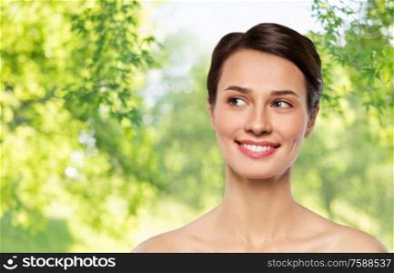 beauty, bodycare and people concept - beautiful smiling young woman with bare shoulder over green natural background. beautiful smiling young woman with bare shoulder