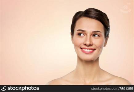 beauty, bodycare and people concept - beautiful smiling young woman with bare shoulder over beige background. beautiful smiling young woman with bare shoulder