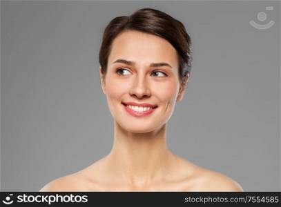 beauty, bodycare and people concept - beautiful smiling young woman with bare shoulder over grey background. beautiful smiling young woman with bare shoulder