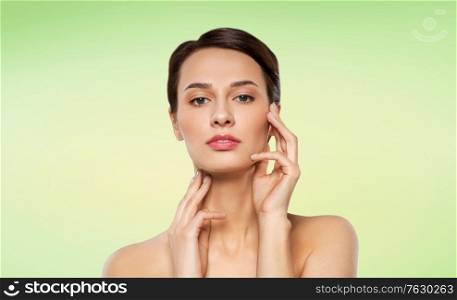 beauty, bodycare and people concept - beautiful young woman touching her face over lime green natural background. beautiful young woman touching her face