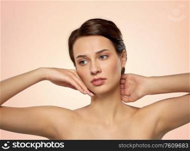 beauty, bodycare and people concept - beautiful young woman touching her face over beige background. beautiful young woman touching her face