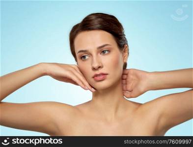 beauty, bodycare and people concept - beautiful young woman touching her face over blue background. beautiful young woman touching her face