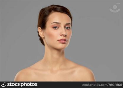 beauty, bodycare and people concept - beautiful young woman with bare shoulder over grey background. beautiful young woman with bare shoulder