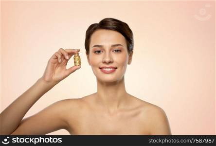 beauty, bodycare and people concept - beautiful young woman with gold facial mask in bottle over beige background. beautiful young woman with gold facial mask