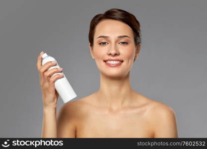 beauty, bodycare and people concept - beautiful young woman with hair spray or mist and bare shoulder over grey background. beautiful young woman with hair spray or mist