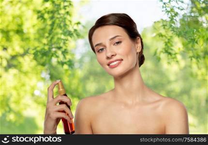 beauty, bodycare and people concept - beautiful young woman with sun protective oil over green natural background. beautiful young woman with sun protective oil