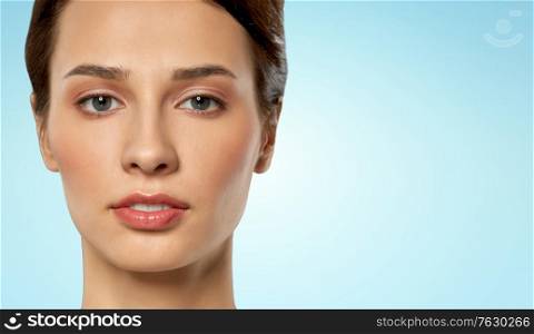 beauty, bodycare and people concept - close up of beautiful young woman face over blue background. close up of beautiful young woman face