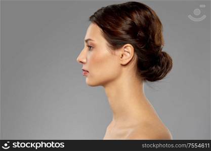 beauty, bodycare and people concept - profile of beautiful young woman with bare shoulders over grey background. profile of beautiful woman with bare shoulders
