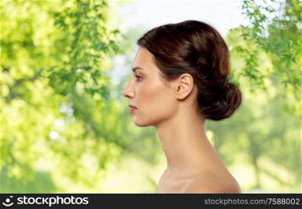 beauty, bodycare and people concept - profile of beautiful young woman with bare shoulders over green natural background. profile of beautiful woman with bare shoulders