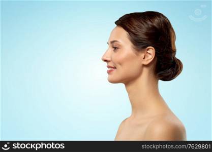 beauty, bodycare and people concept - profile of beautiful young woman with bare shoulders over blue background. profile of beautiful woman with bare shoulders