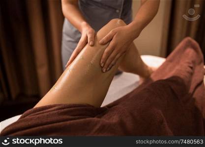 beauty, bodycare and relaxation concept - close up of woman lying and having leg massage with gel at spa. woman lying and having leg massage with gel at spa
