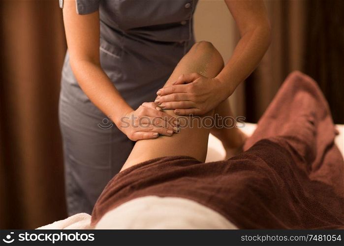 beauty, bodycare and relaxation concept - close up of woman lying and having leg massage with gel at spa. woman lying and having leg massage with gel at spa