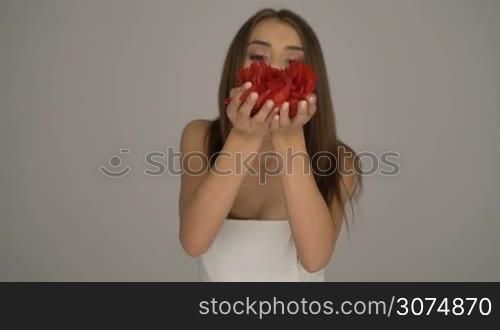 Beauty brunette woman blowing rose petals slow motion video