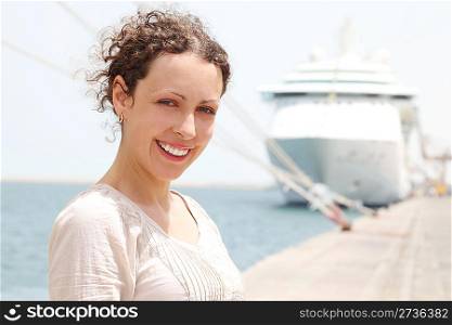 beauty brunette woman smiling and looking at camera, big cruise liner on background