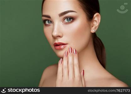 Beauty brunette woman with perfect makeup. Glamour girl. Red lips and nails. Perfect eyebrows. Skin care foundation. Beauty girls face isolated on green background. Fashion photo