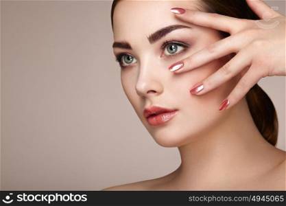 Beauty brunette woman with perfect makeup. Red lips and nails. Perfect eyebrows. Skin care foundation. Beauty girls face isolated on beige background. Fashion photo