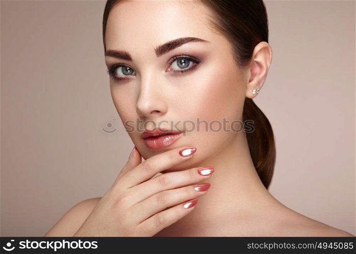 Beauty brunette woman with perfect makeup. Red lips and nails. Perfect eyebrows. Skin care foundation. Beauty girls face isolated on beige background. Fashion photo