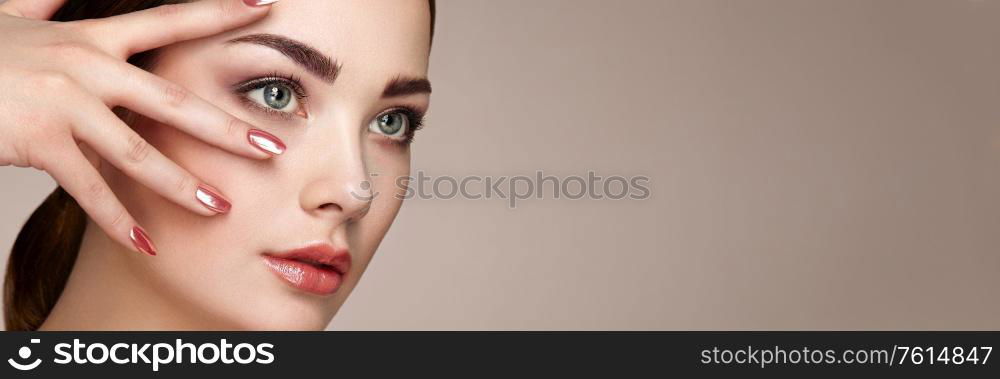 Beauty brunette woman with perfect makeup. Red lips and nails. Perfect eyebrows. Skin care foundation. Beauty girls face isolated on beige background. Fashion photo