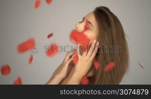Beauty brunette woman with rose petals falling down wearing white dress