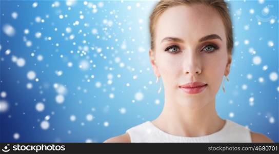 beauty, christmas, holidays and people concept - face of beautiful woman or bride in white dress over blue background and snow