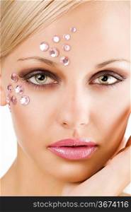 beauty close up portrait of a pretty young woman with pink crystal stones as make on face