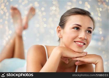 beauty, comfort and people concept - beautiful happy young woman lying on bed at home bedroom. beautiful happy young woman lying on bed at home