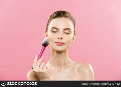 Beauty Concept - Closeup Beautiful caucasian woman applying makeup with Cosmetic Powder Brush. Perfect Skin. Isolated on pink background and copy space. Beauty Concept - Closeup Beautiful caucasian woman applying makeup with Cosmetic Powder Brush. Perfect Skin. Isolated on pink background and copy space.