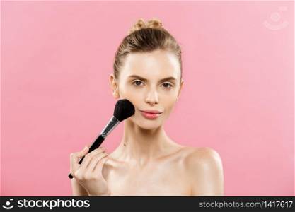 Beauty Concept - Closeup Beautiful caucasian woman applying makeup with Cosmetic Powder Brush. Perfect Skin. Isolated on pink background and copy space. Beauty Concept - Closeup Beautiful caucasian woman applying makeup with Cosmetic Powder Brush. Perfect Skin. Isolated on pink background and copy space.