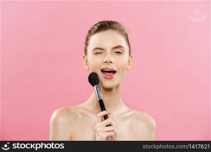 Beauty Concept - Closeup Beautiful caucasian woman applying makeup with Cosmetic Powder Brush. Perfect Skin. Isolated on pink background and copy space. Beauty Concept - Closeup Beautiful caucasian woman applying makeup with Cosmetic Powder Brush. Perfect Skin. Isolated on pink background and copy space.