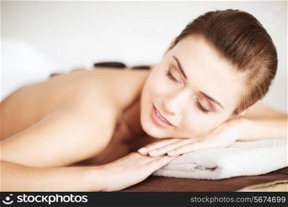 beauty concept - woman in spa salon with hot stones