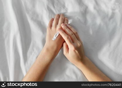 beauty, cosmetics and bodycare concept - woman applying moisturizing hand cream at home. woman applying hand cream at home