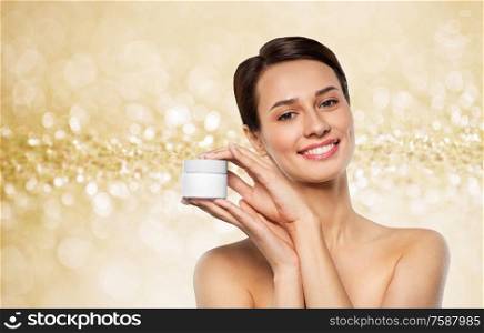 beauty, cosmetics and skincare concept - happy young woman holding jar of cream over shimmering golden glitter on background. happy young woman holding jar of cream