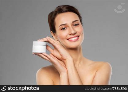 beauty, cosmetics and skincare concept - happy young woman holding jar of cream over grey background. happy young woman holding jar of cream