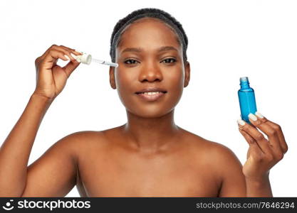 beauty, cosmetics and skincare concept - portrait of happy smiling young african american woman with bare shoulders holding bottle of serum over grey background. african american woman with bottle of serum