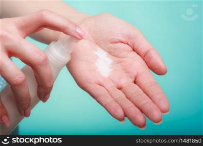 Beauty, cosmetics, concept. Woman applying white moisturizing cream from bottle with pump on hand to test product. Woman putting white cream on hand