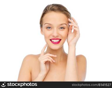 beauty, cosmetics, people and health concept - smiling young woman with pink lipstick on lips touching her face